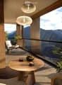 Balcony with wooden table, chairs, bowl of fruit, and a view of mountains.