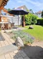 Garden with a patio area, outdoor dining set, umbrella, bicycle, and surrounding greenery.
