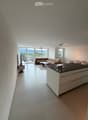 Modern open-plan living and dining area with a sectional sofa, coffee table, kitchen island, and large windows offering a scenic view.