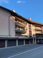 Multi-story residential building with balconies, garage, and parking area.