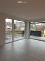 Empty room with large sliding glass doors leading to a balcony, tiled floor, and bright natural light.
