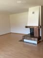 Empty room with wooden flooring, white walls, and a built-in brick fireplace.