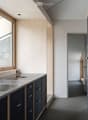 Modern kitchen with stainless steel sink, sleek faucet, and dark blue cabinets with silver handles. Large window provides natural light.