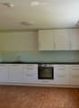 Modern kitchen with white cabinets, wooden flooring, and built-in appliances including a sink, faucet, and oven.