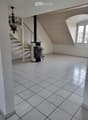 Hallway with tiled floor, staircase, and wood-burning stove with tools nearby.