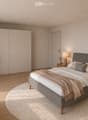 Modern bedroom with a large bed, nightstands, lamps, a round rug, and decorative plants and vases.