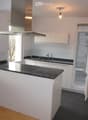 modern kitchen with island, granite countertops, stainless steel appliances, white cabinets, open refrigerator, sink with faucet, exhaust hood, wooden floor