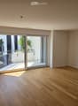 Empty room with wooden flooring and large sliding glass doors leading to a balcony area.