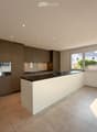 Modern kitchen with grey cabinetry, white island, black countertop, and stainless steel sink.