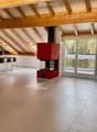 Open-plan living and kitchen area with exposed wooden beams, a modern fireplace, and large sliding glass doors leading to a balcony.