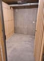 Empty room with unfinished concrete walls and floor, wooden framing on the sides, and exposed ductwork on the ceiling.