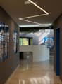 Modern hallway with sleek design, large windows, and geometric wall art. Features a curved white partition and recessed lighting.