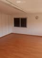 Empty room with wooden flooring, white walls, built-in wardrobes, and large windows allowing natural light.