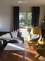 Modern living room with a grey sectional sofa, yellow chairs, a white coffee table, and a fireplace with a vase of sunflowers on the mantel.