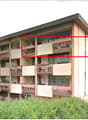 Multi-story apartment building with balconies and large windows, surrounded by greenery and mountains.