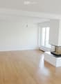 Empty room with light wooden flooring, white walls, and a built-in fireplace with a glass front.