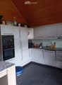modern kitchen with white cabinets, black tiled floor, granite countertop, built-in oven, dishwasher, sink, and various kitchen appliances