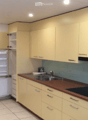 Modern kitchen with light-colored cabinets, a stainless steel sink, and a built-in stove. The refrigerator is open, revealing its interior.