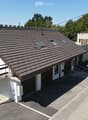 Two-story house with a tiled roof, white exterior, garage, and small balcony with wooden stairs.