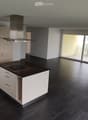 Modern kitchen with white cabinets, black countertops, induction cooktop, and large sliding glass doors leading to a balcony.