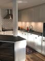 Modern kitchen with white cabinets, black countertops, stainless steel appliances, and a central island. Features a sink, faucet, and decorative vase on the counter.