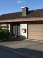 Two-story house with a tiled roof, garage, and a small garden area.