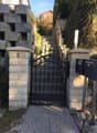Stone entrance pillars, black wrought iron gate, stone walkway, metal handrails, stone steps, mailboxes on right, number 8 on left pillar.