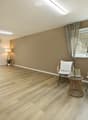 Empty room with wooden flooring, large windows, and neutral-colored walls. No furniture or equipment present.