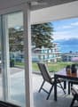 Balcony with a view of a lake and mountains, featuring a sofa, coffee table, and outdoor dining set.