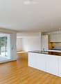 Modern kitchen with white cabinets, a central island, and large sliding glass doors leading to a balcony.
