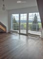 Empty room with wooden flooring, large windows, and a staircase leading upwards.
