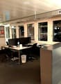Modern office space with desks, chairs, computers, and large windows overlooking the city.