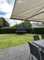 Backyard with a trampoline, swing set, patio furniture, and covered seating area.