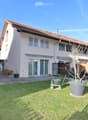 Well-maintained garden with a lawn, potted plants, a barbecue area, and a patio with outdoor furniture.