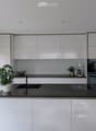 Modern kitchen with white cabinets, black countertop, sink, coffee maker, oven, and decorative plant.
