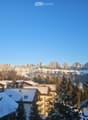 Mountainous area with snow-covered buildings and a snowy mountain range in the background.
