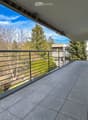 Balcony with tiled floor, metal railing, and a view of trees and a building in the background.