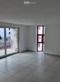 Empty room with tiled floor, white walls, large window, and sliding glass door leading to a balcony area.