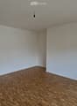 Empty room with wooden flooring, white walls, and large sliding glass doors leading to a balcony or outdoor area.