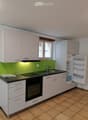 Modern kitchen with white cabinets, black countertops, induction cooktop, sink, and open refrigerator.