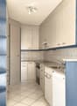 modern kitchen, white cabinets, blue shelves, granite countertop, stainless steel sink, dishwasher, washing machine, ceiling lights