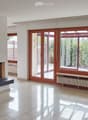 Empty living room with tiled floor, large windows, fireplace, radiator, and sliding glass doors leading to a balcony.