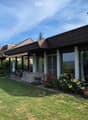 Well-maintained garden with a lawn, patio seating area, covered outdoor space, and colorful flower beds.