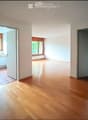 Empty room with wooden flooring and white walls, featuring three open doorways leading to other rooms.
