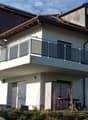 Two-story house with a balcony, modern design, and a small outdoor seating area with a table and chairs.