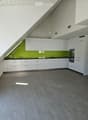 Modern kitchen with white cabinets, grey tiled floor, green backsplash, and built-in oven.