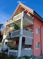 3 story house, red brick, white windows, balcony, plants