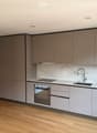 Modern kitchen with grey cabinets, marble backsplash, and wooden flooring.