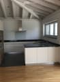 Modern kitchen with white cabinets, black countertops, and a wooden accent wall. Features a sink, faucet, and an oven.