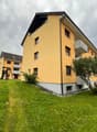 2 story yellow house, white trim, multiple balconies, large grassy yard